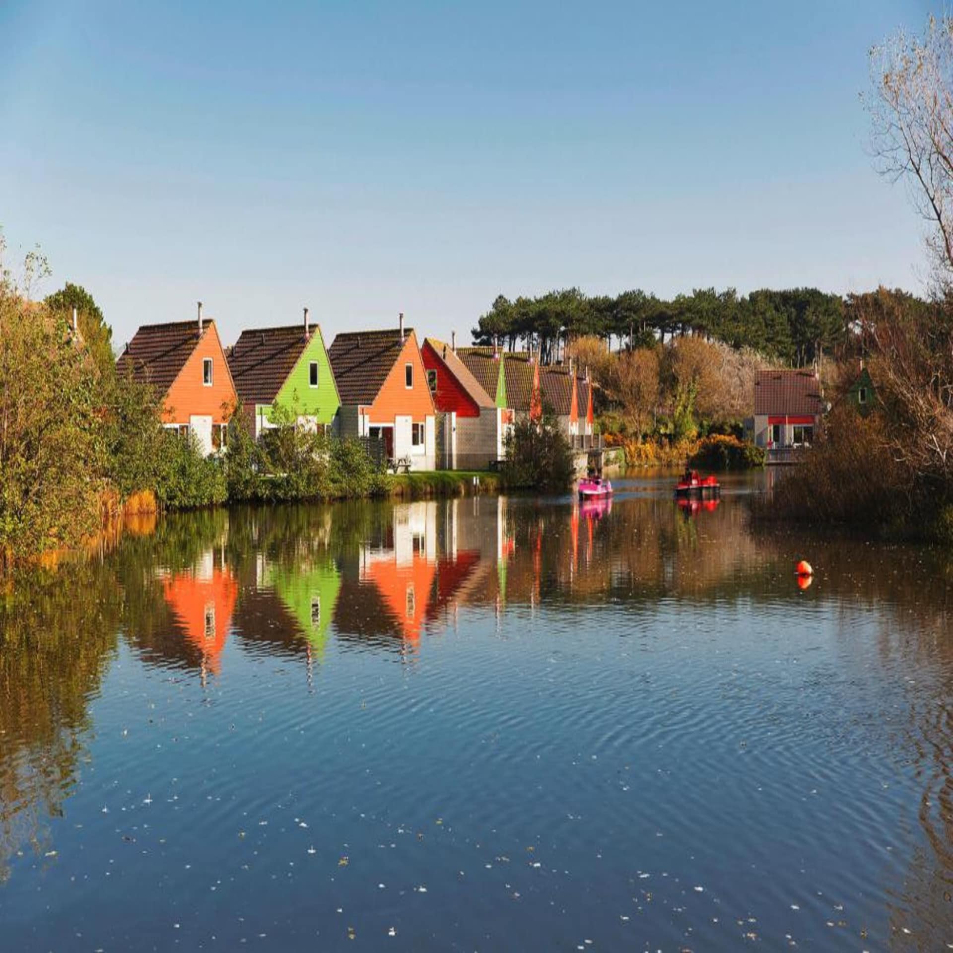 Bunte Ferienhäuser spiegeln sich im Wasser.