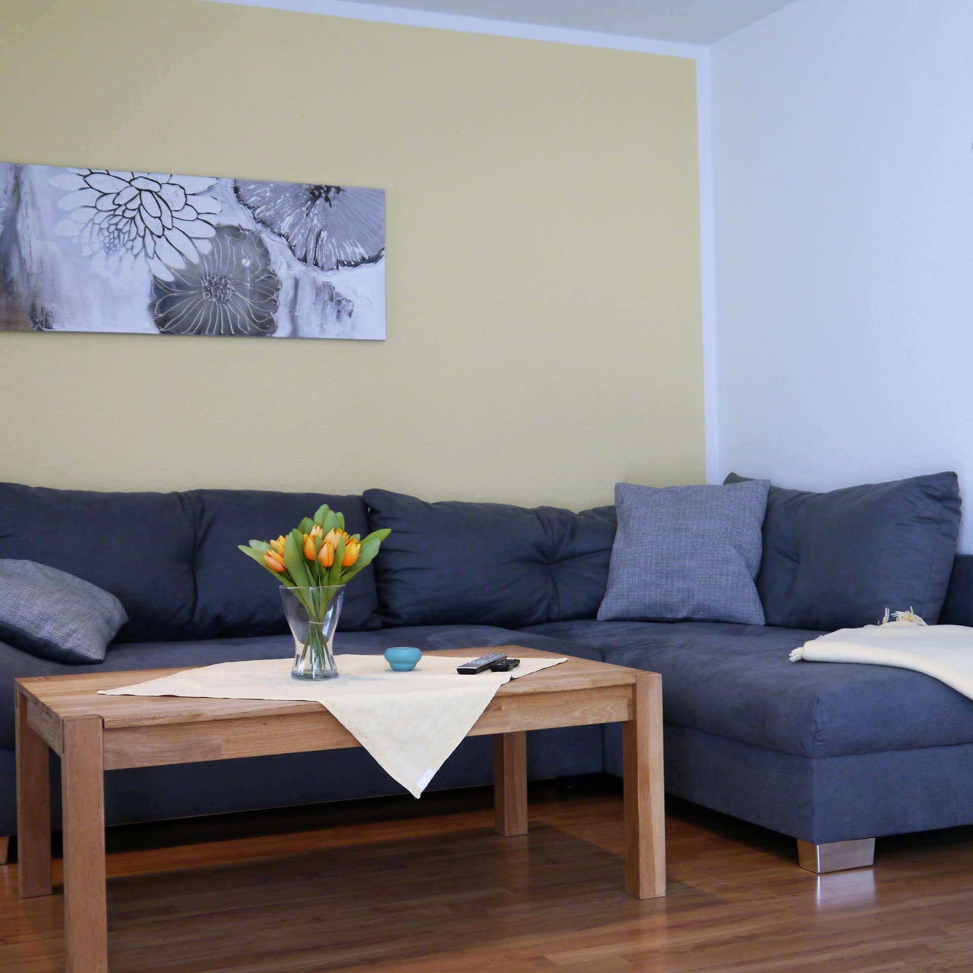 Wohnzimmer mit blauem Sofa und Holztisch mit Blumenstrauß einer Ferienwohnung in Prerow