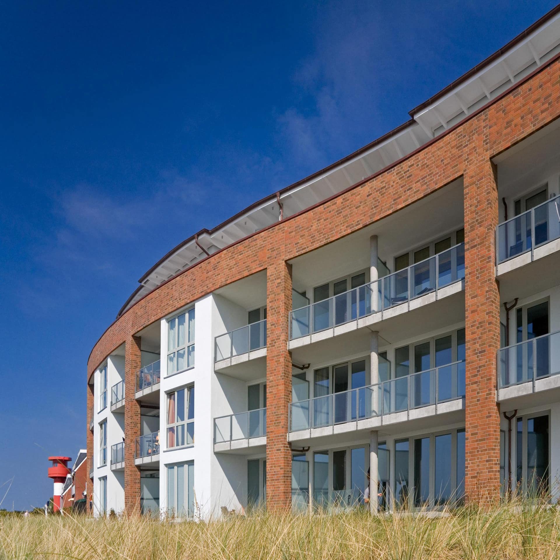 3-stöckiges, rot-weißes Apartmenthaus direkt am Strand.