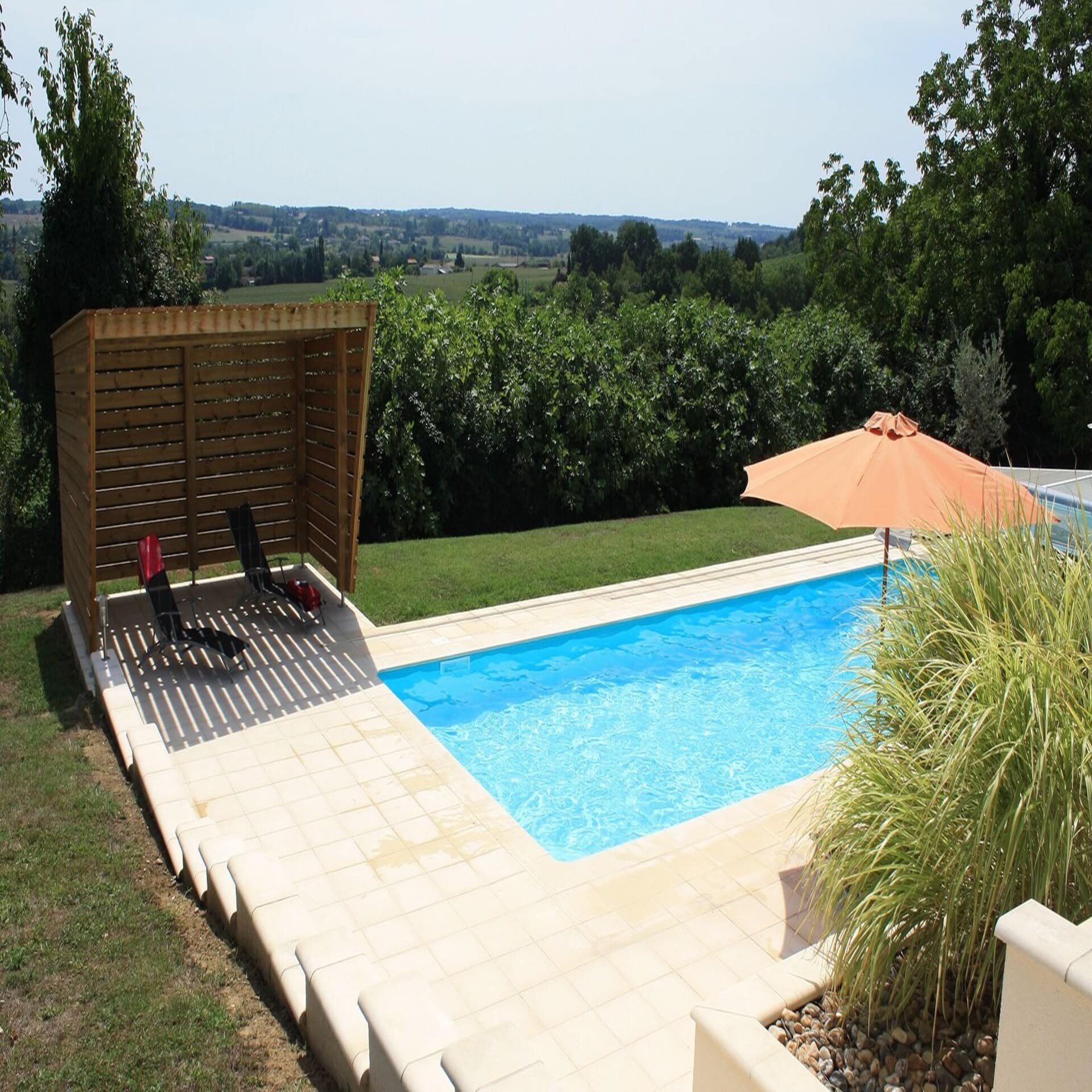 Garten mit Pool und Sonnenliegen und Terrasse sowie Blick auf die Weinberge um Bordeaux. 