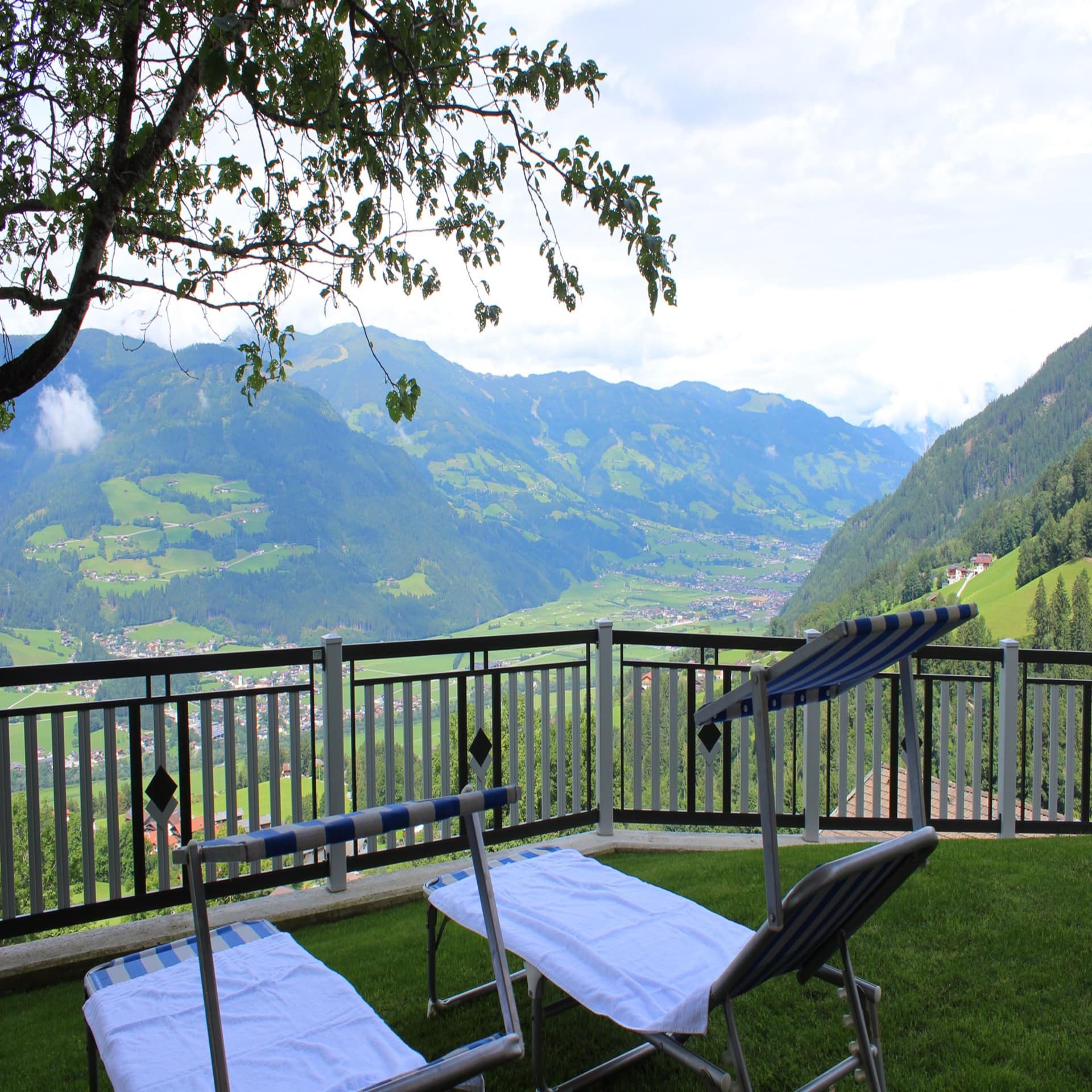 2 Sonnenliegen mit Sonnenschutz in einem umzäunten Garten und Blick auf das Umland.