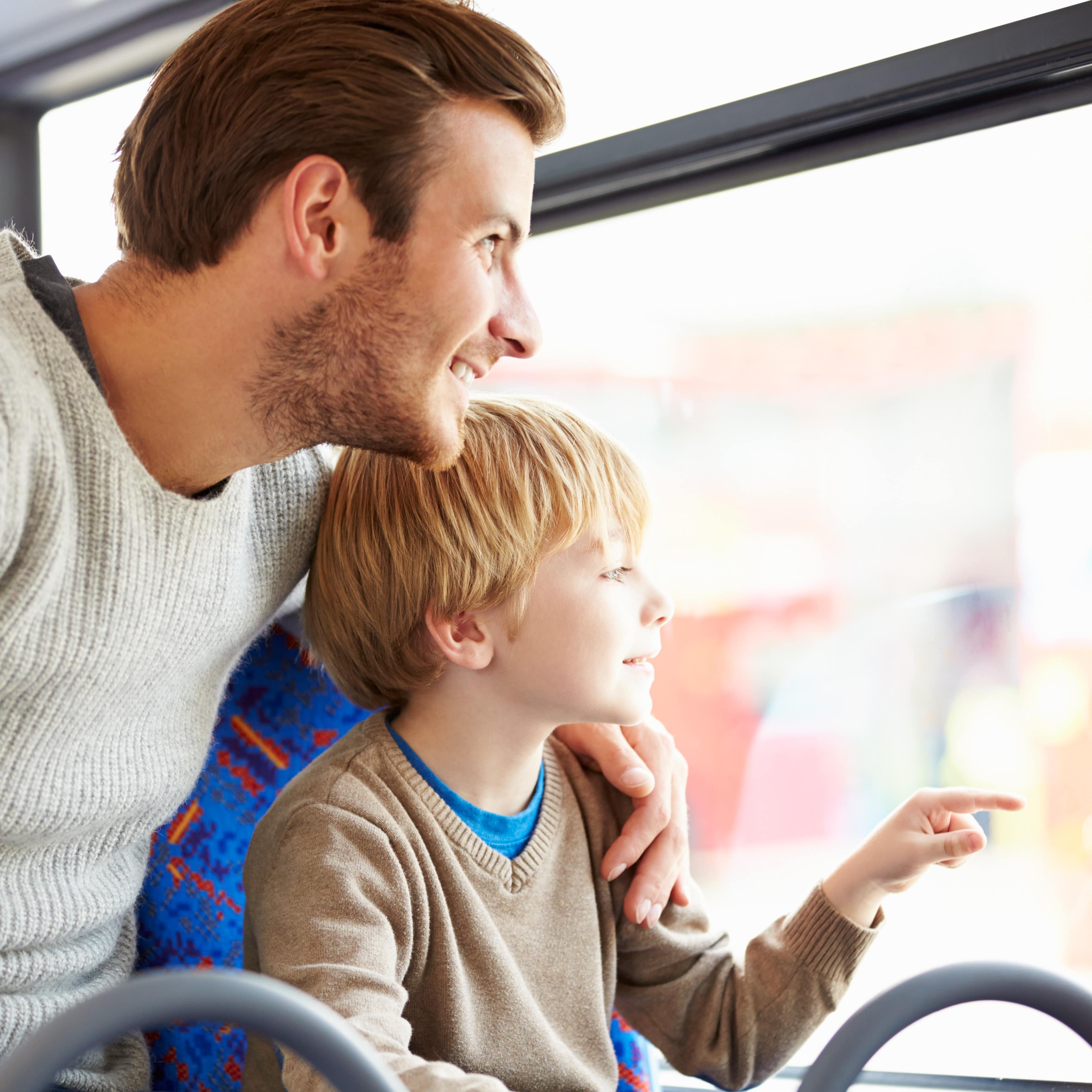 Nahaufnahme: Vater und Sohn schauen in einem Bus aus dem Fenster.