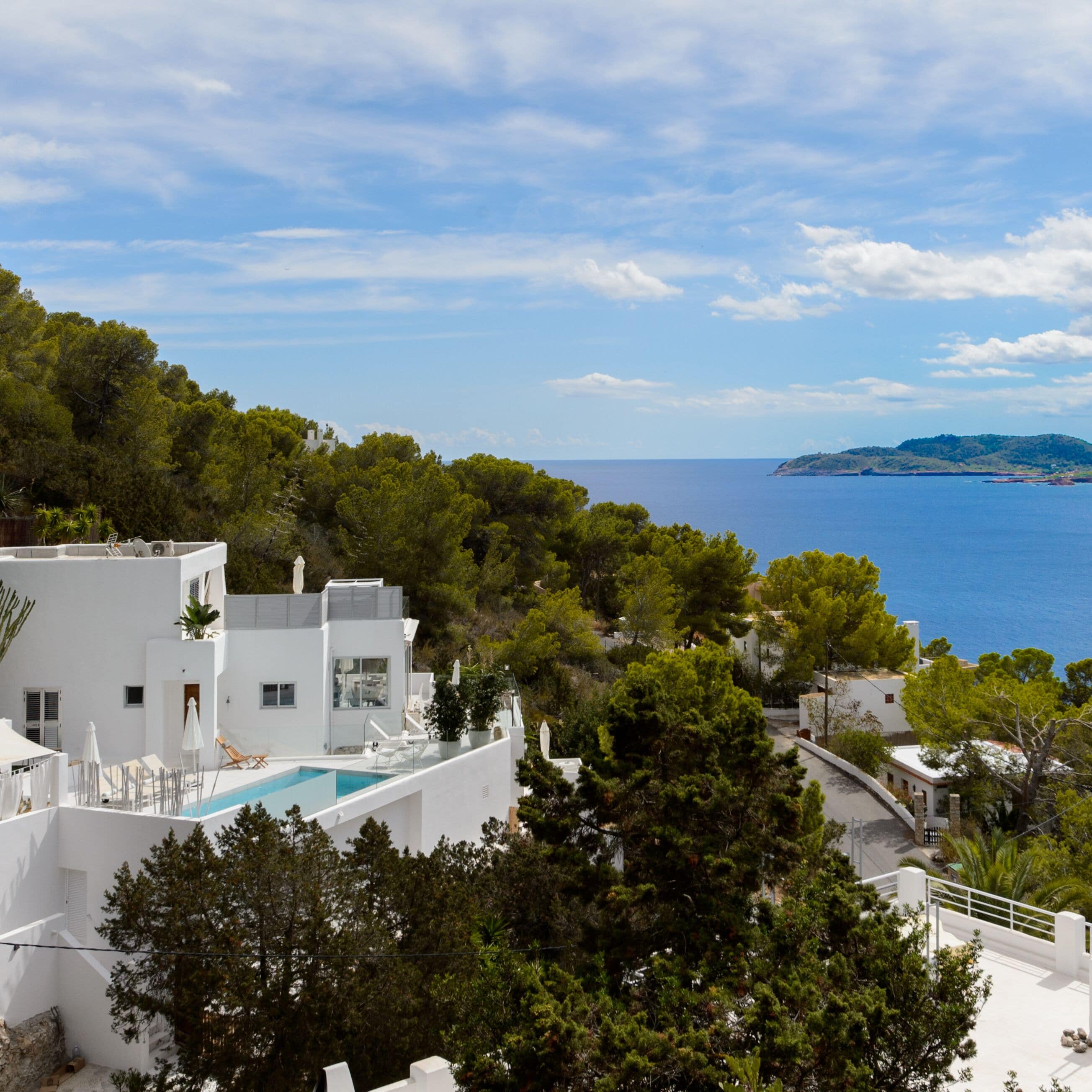 Großes weißes Ferienhaus auf Ibiza umgeben von viel Grün und wenige Schritte vom Meer entfernt