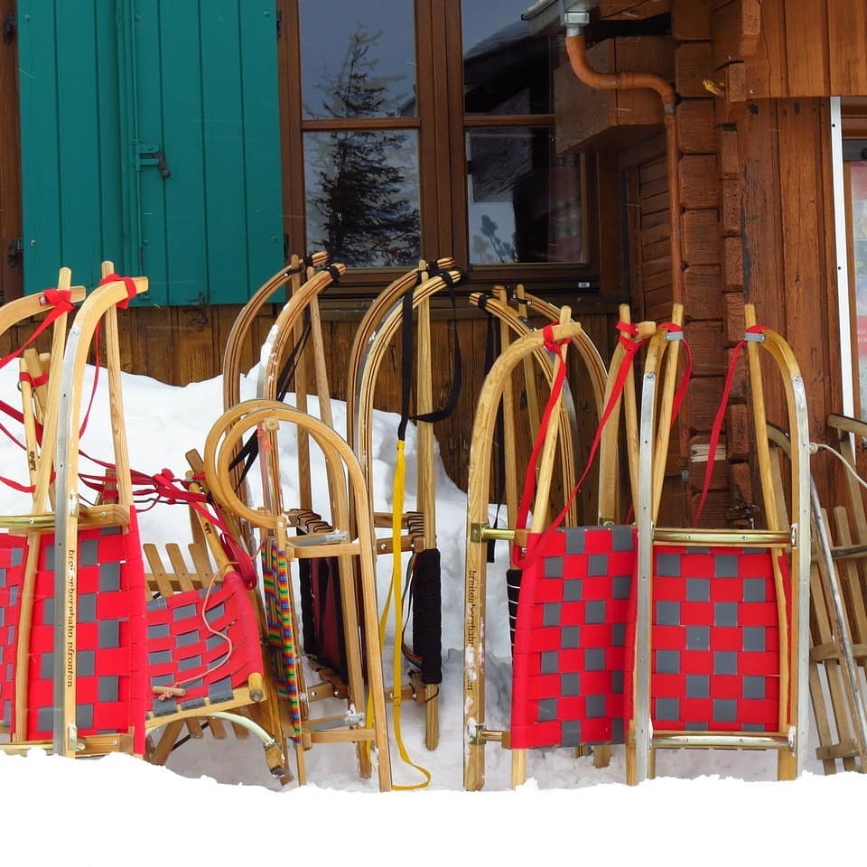Eine Hütte mit Schnee und rot-grau gemusterten Schlitten davor