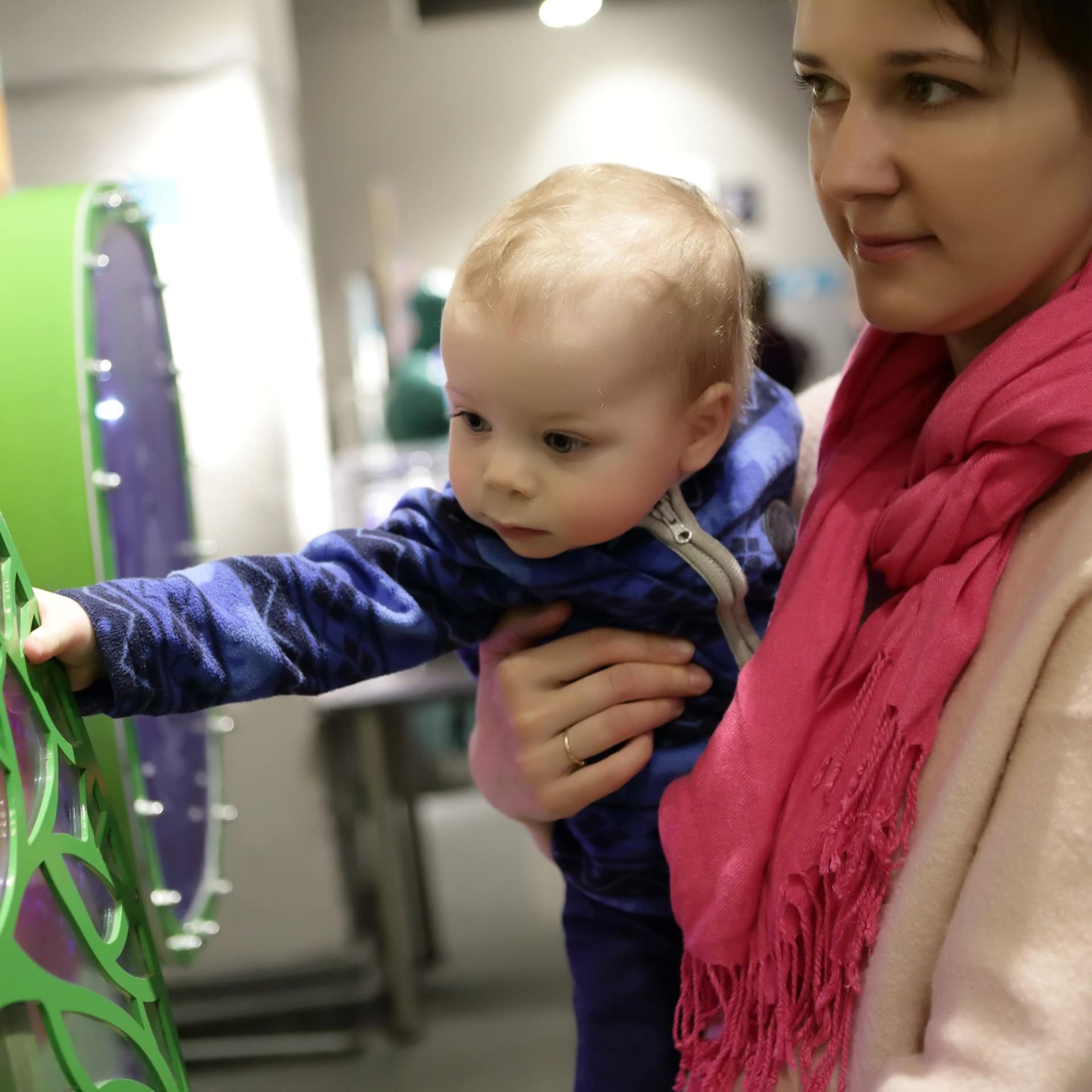 Mutter und Baby im Museum. Das Baby betastet ein Ausstellungsstück.