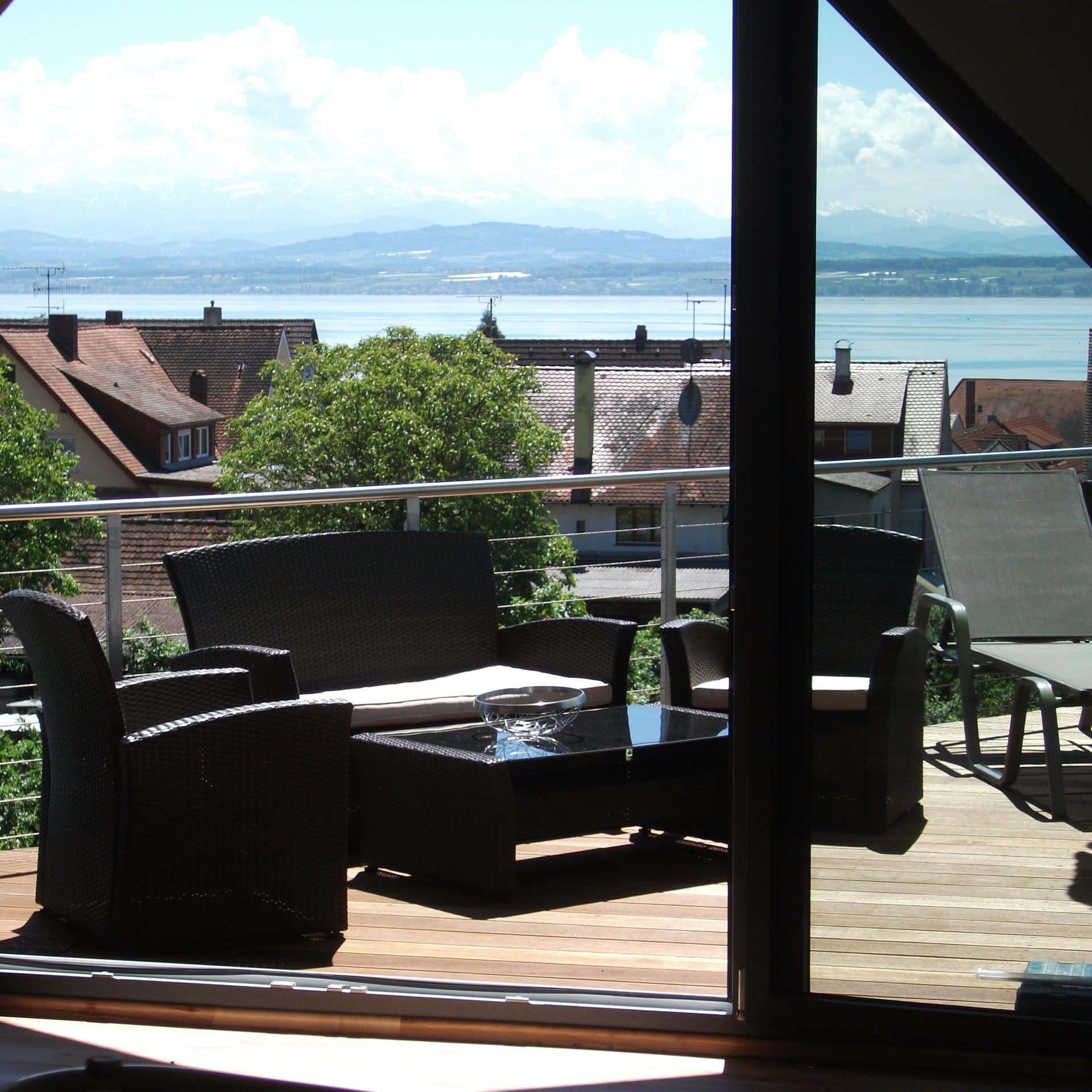 Blick aus dem Wohnzimmer einer Meersburger Ferienwohnung auf die Terrasse mit Blick auf den See und die Alpen