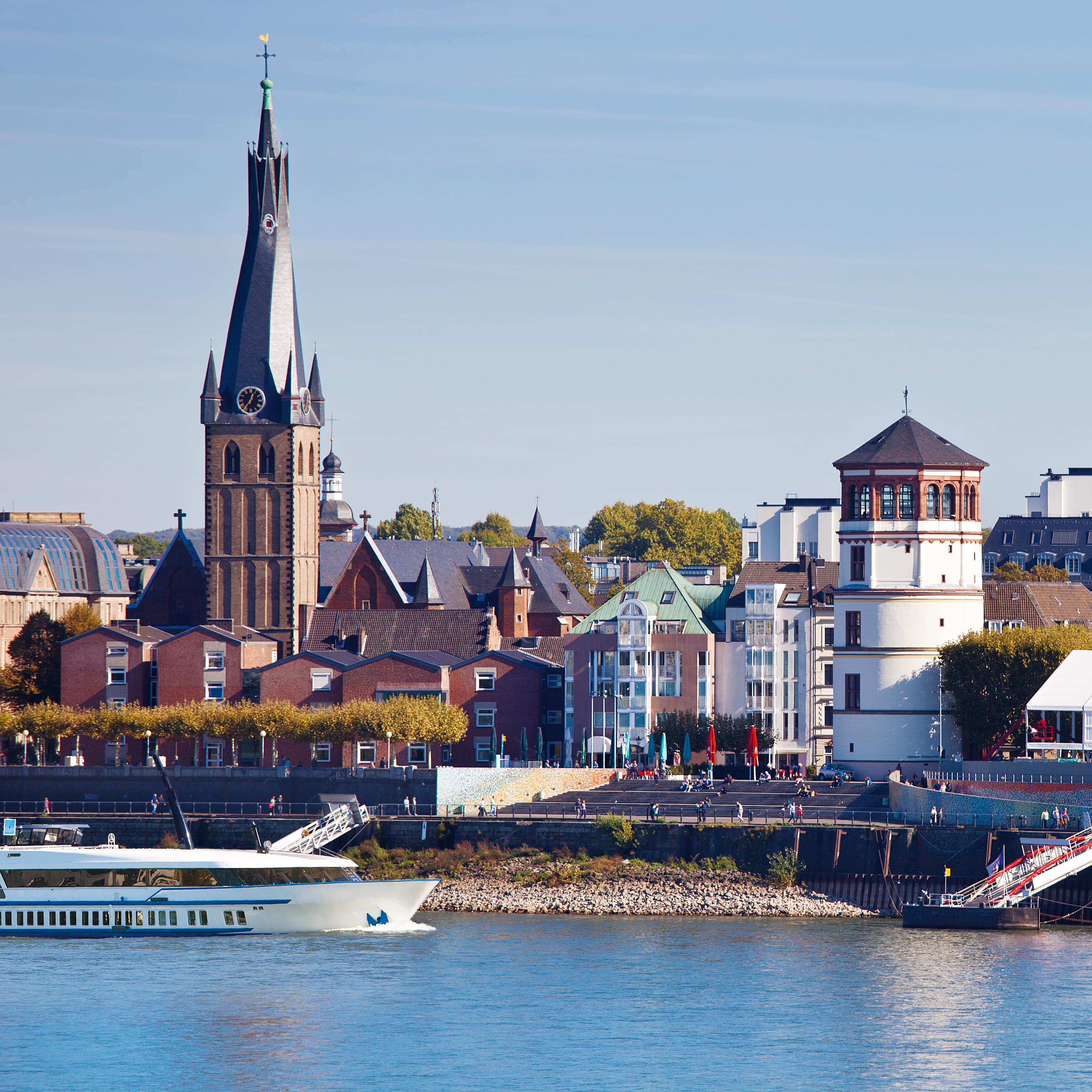 Blick über den Rhein auf die Altstadt von Düsseldorf und ein Ausflugsboot.