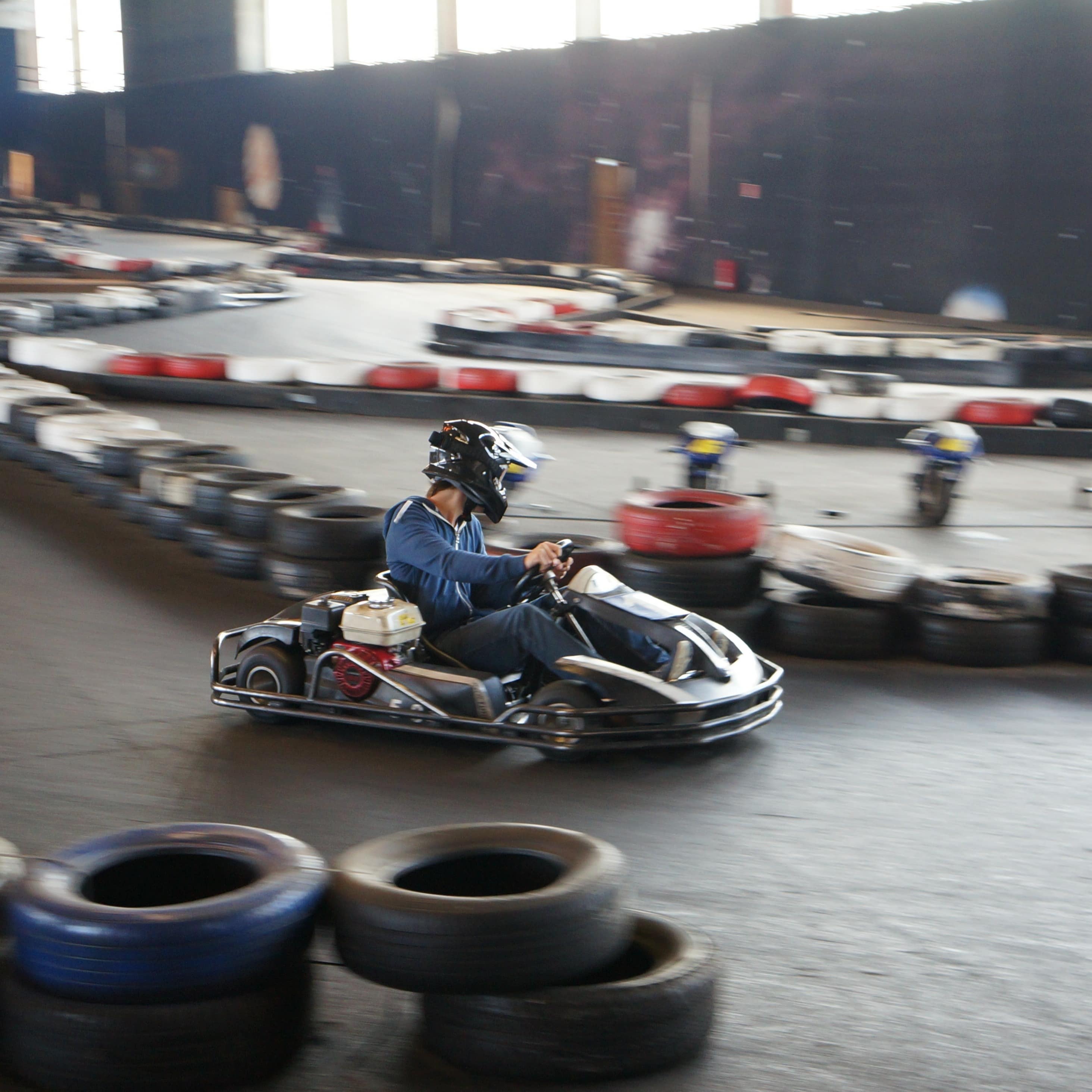 Ein June mit Helm fährt auf einer Go-Kart Bahn.