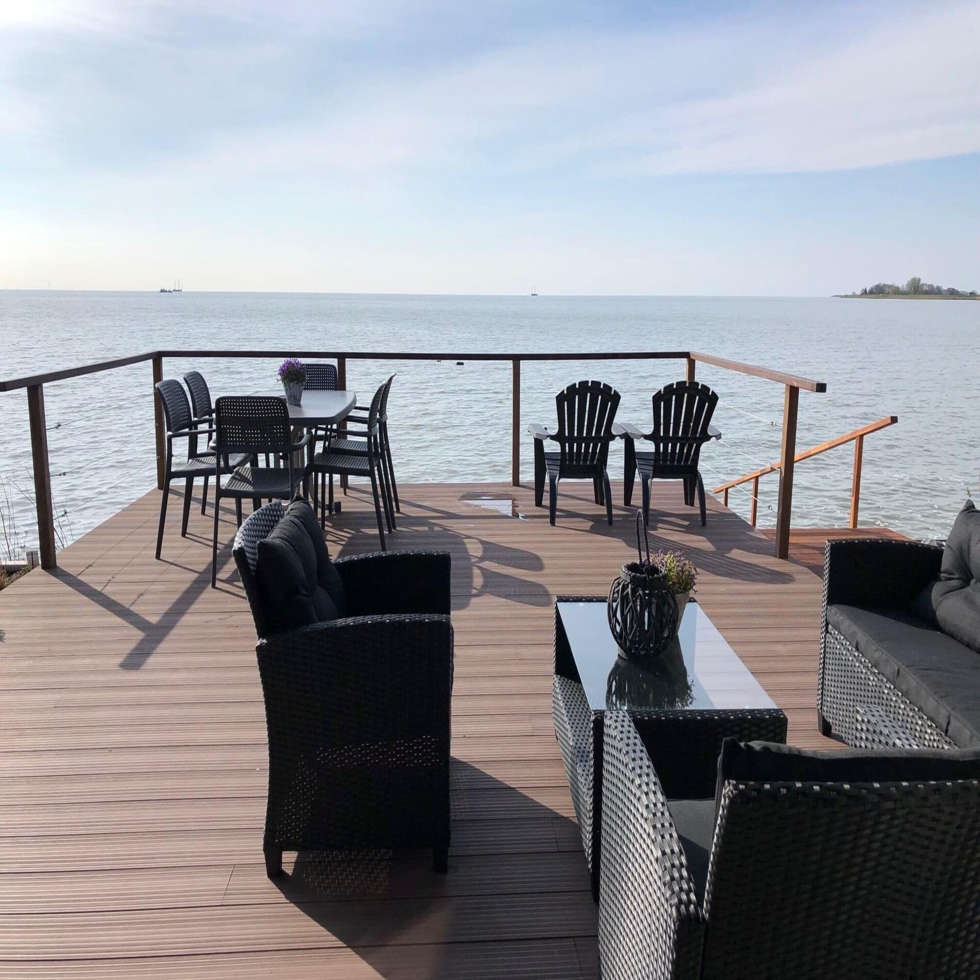 Große Holzterrasse mit Sitzgelegenheiten direkt am Meer. 