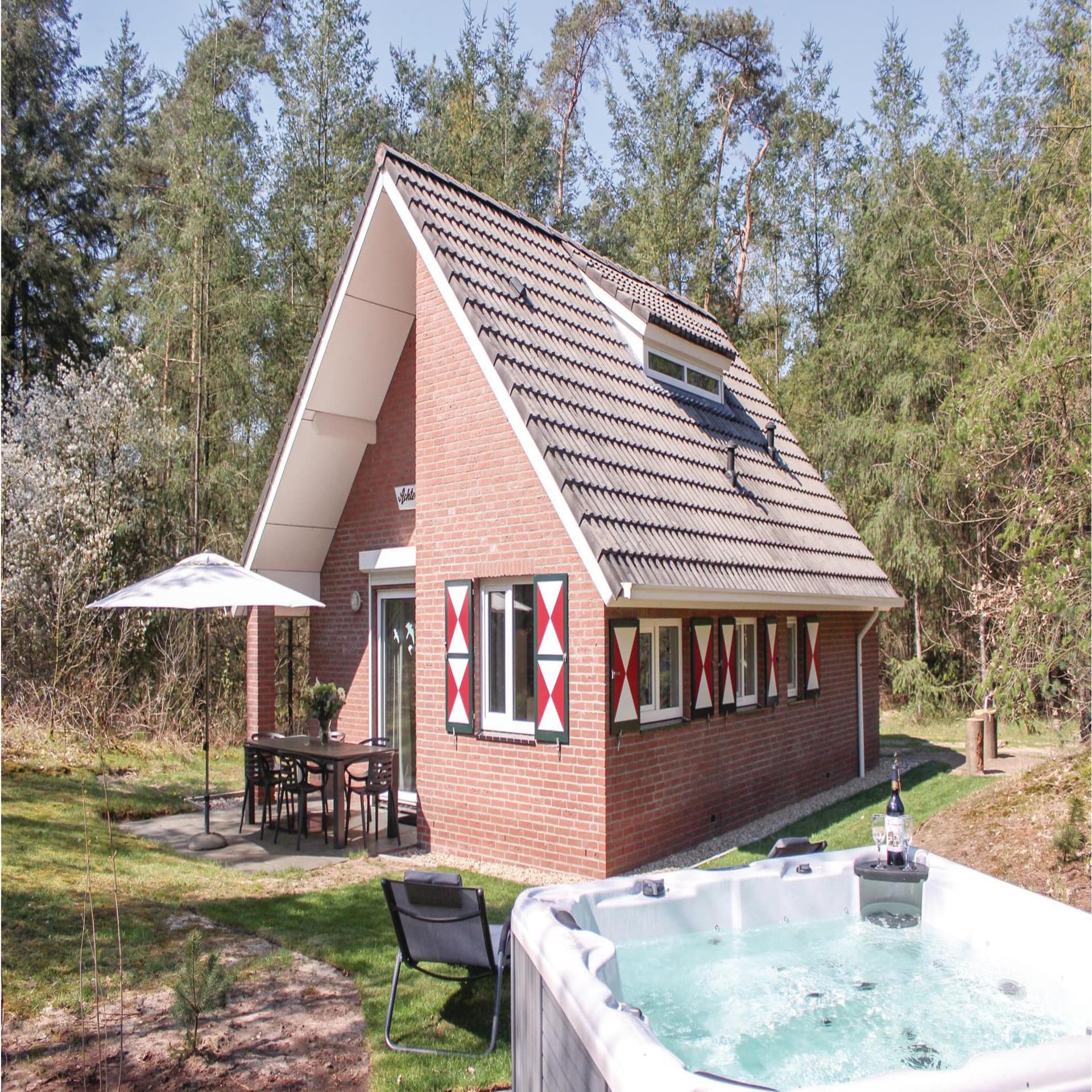 Rotes Ferienhäuschen im Wals mit Whirlpool im Garten.