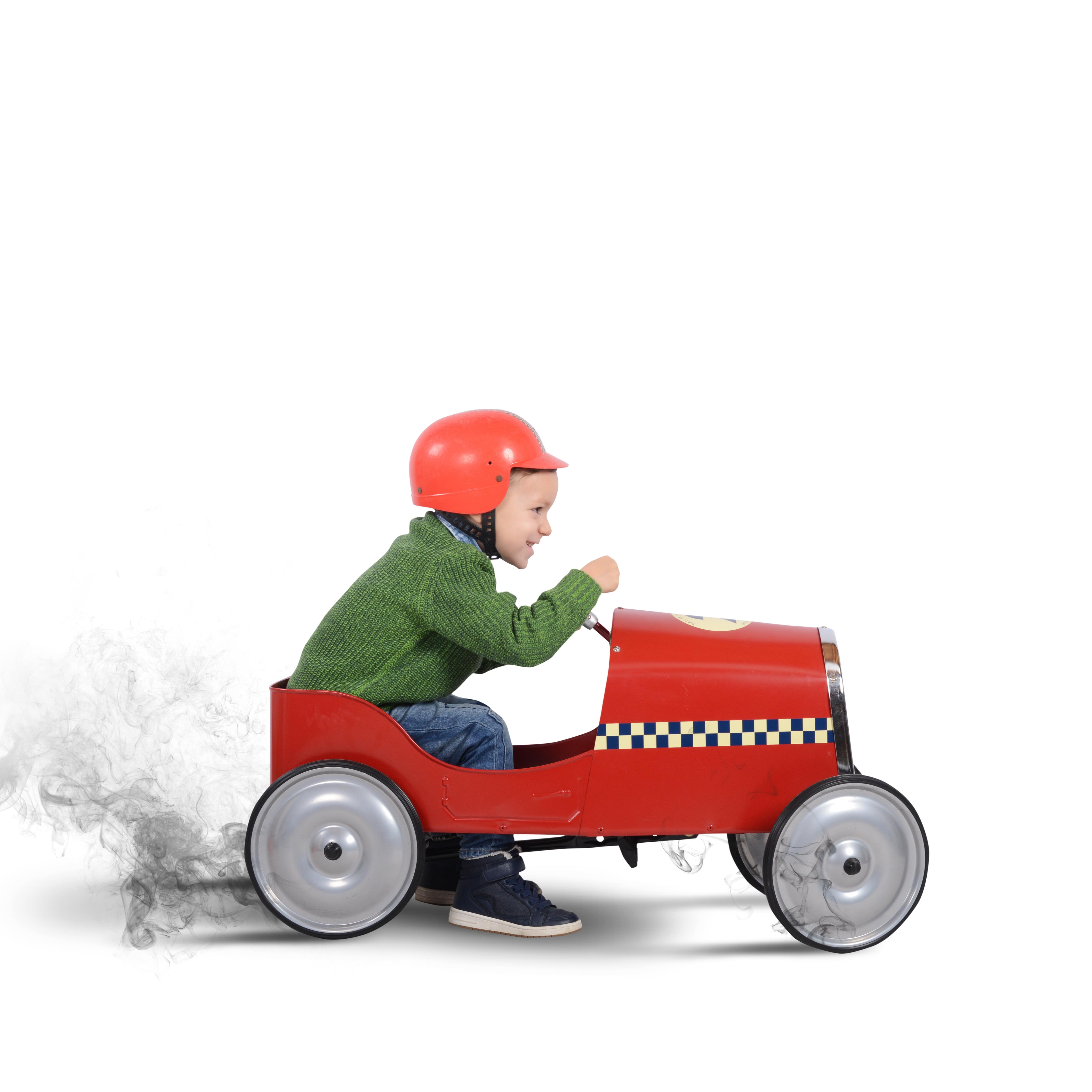Junge in grünem Pulli und mit Helm in einem Spielzeugauto.