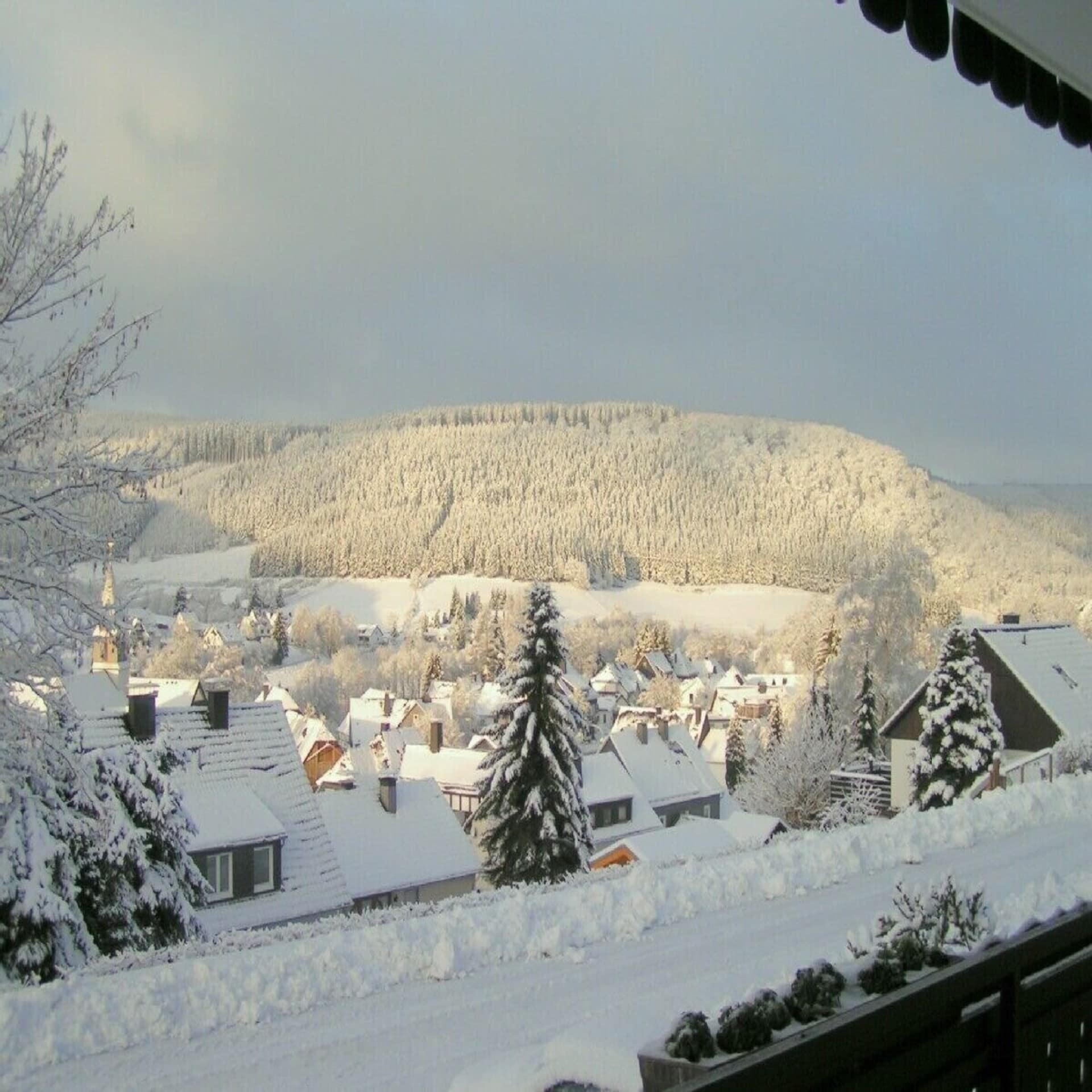 Blick von einem Balkon auf das stark verschneite Winterberg und die Umgebung bei Sonnenschein.