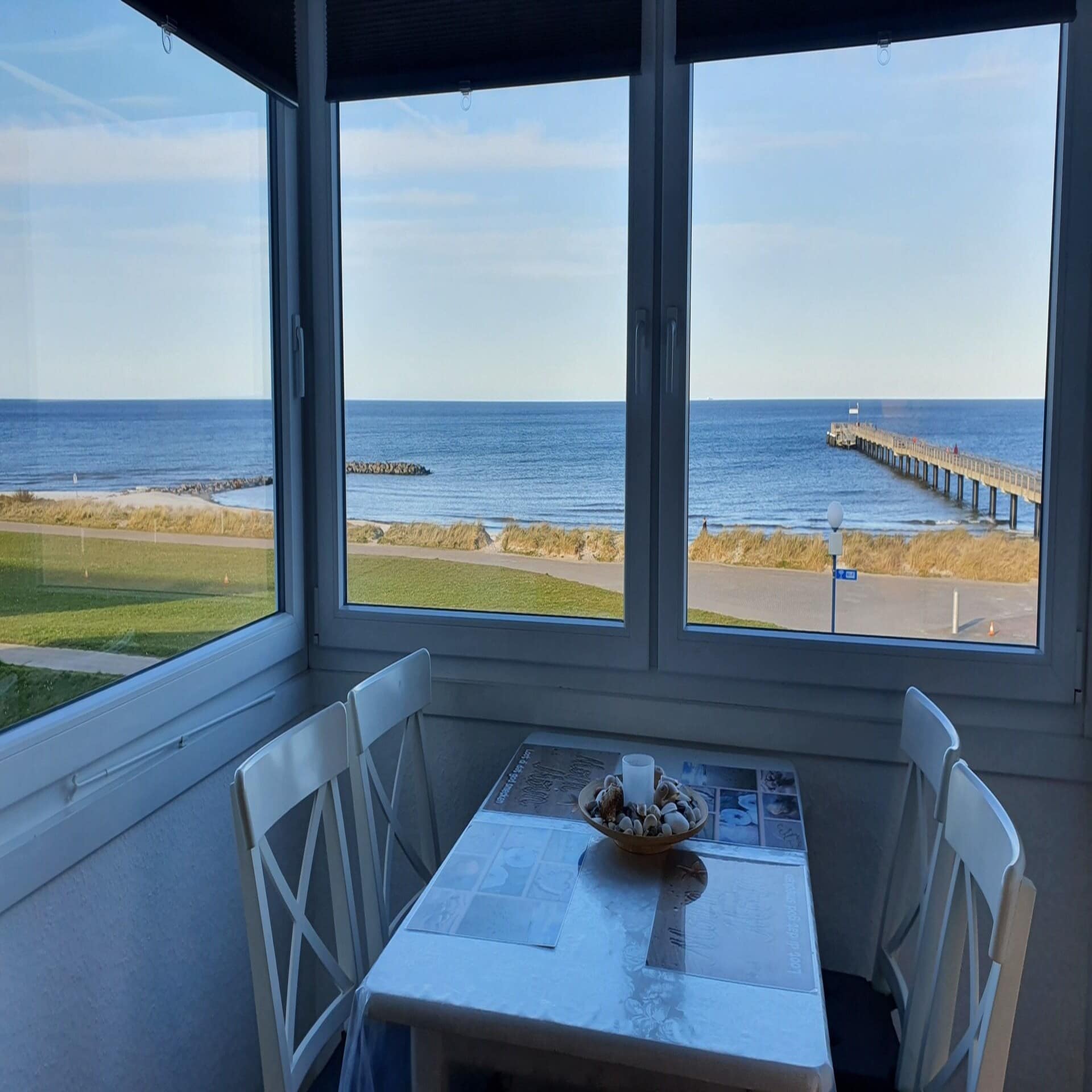 Blick von einem Esszimmer auf die Ostsee und eine Seebrücke. 