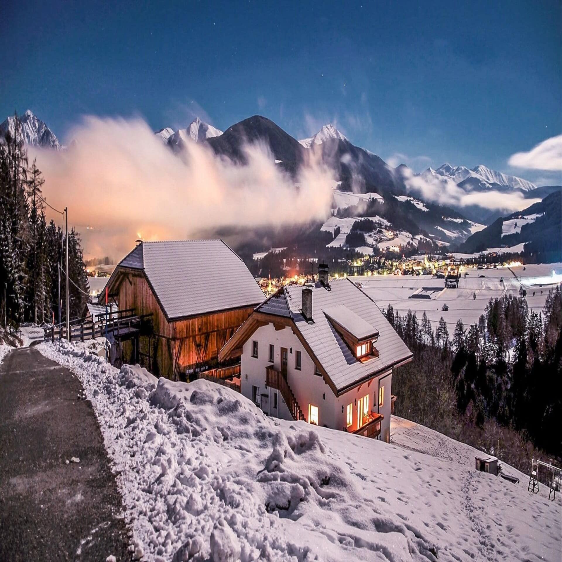 Panoramablick bei Sonnenuntergang im Winter auf einen verschneiten Bauernhof und die Umgebung. 