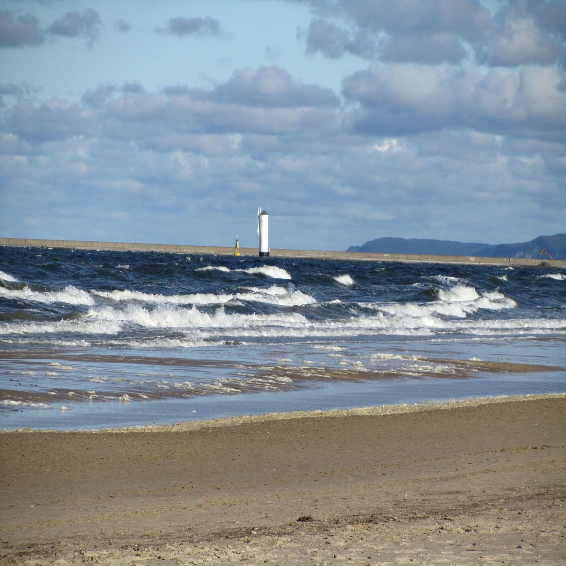 Blick vom Strand auf den weißen Leuchtturm von Swinemünde.
