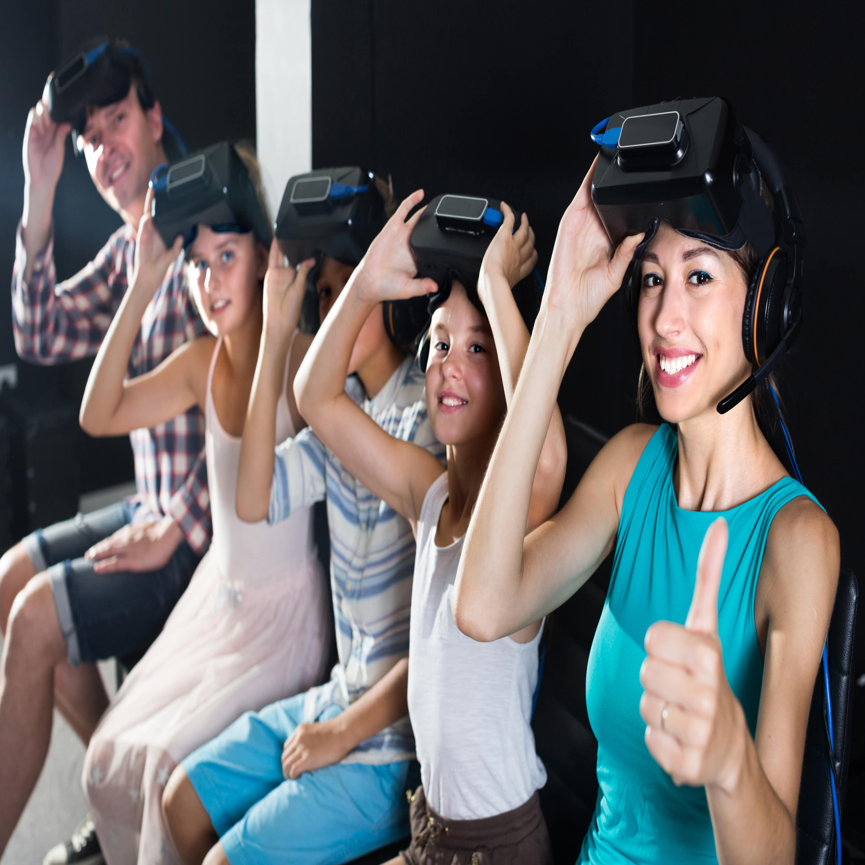 5-köpfige Familie mit hochgeschobenen Virtual-Reality-Brillen schaut in die Kamera.
