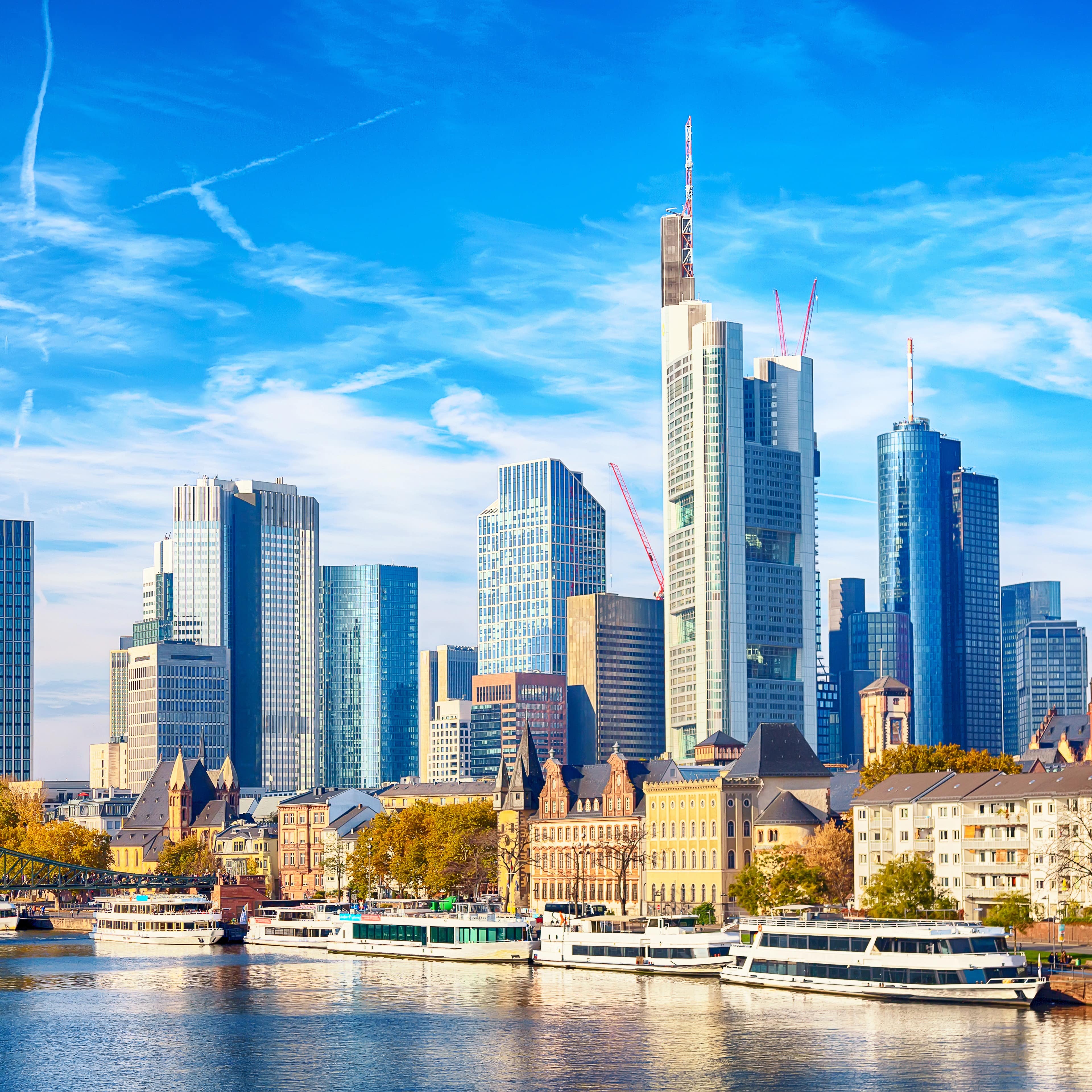 Die Skyline von Frankfurt bei Tageslicht. Vorne der Main.