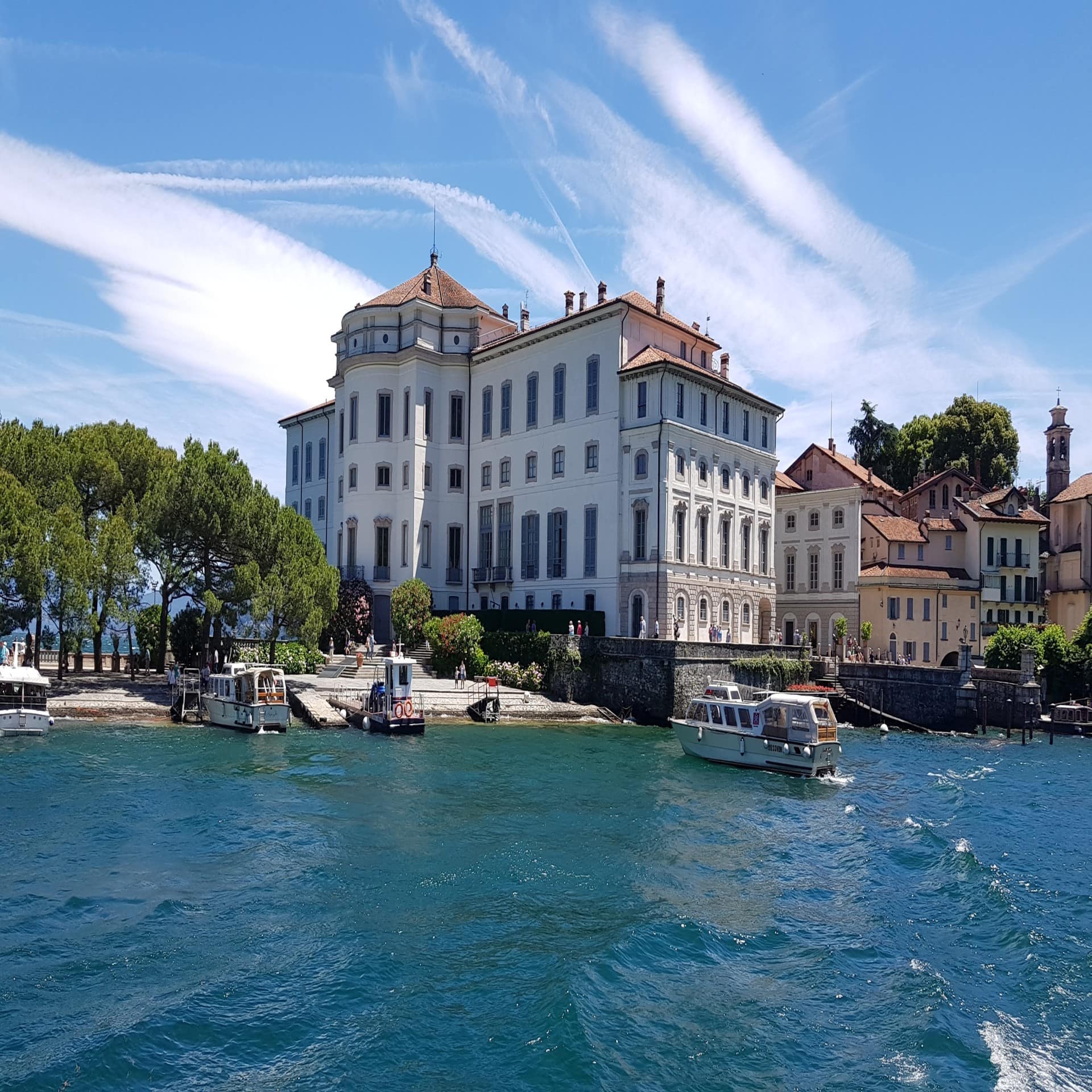 Blick vom Wasser auf den kleinen Hafen von Stresa und die umliegenden Gebäude. 